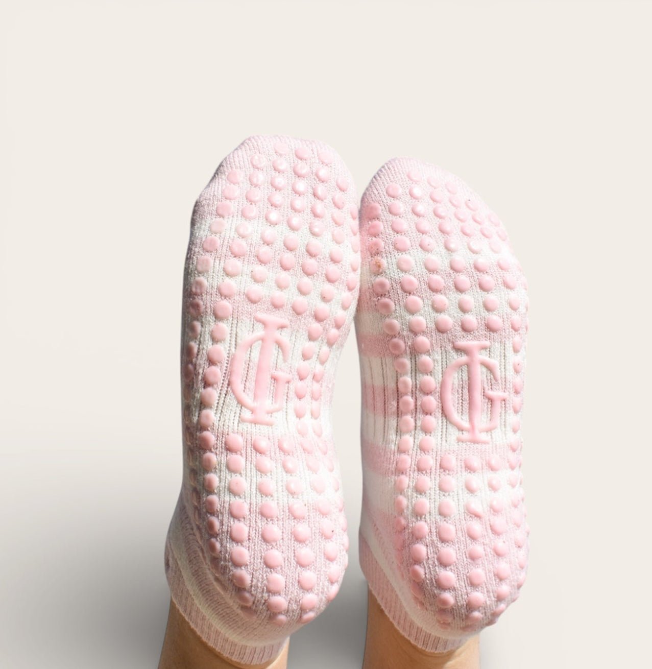 Pair of pink and cream grip pilates socks with textured sole on a white background feminine soft movement
