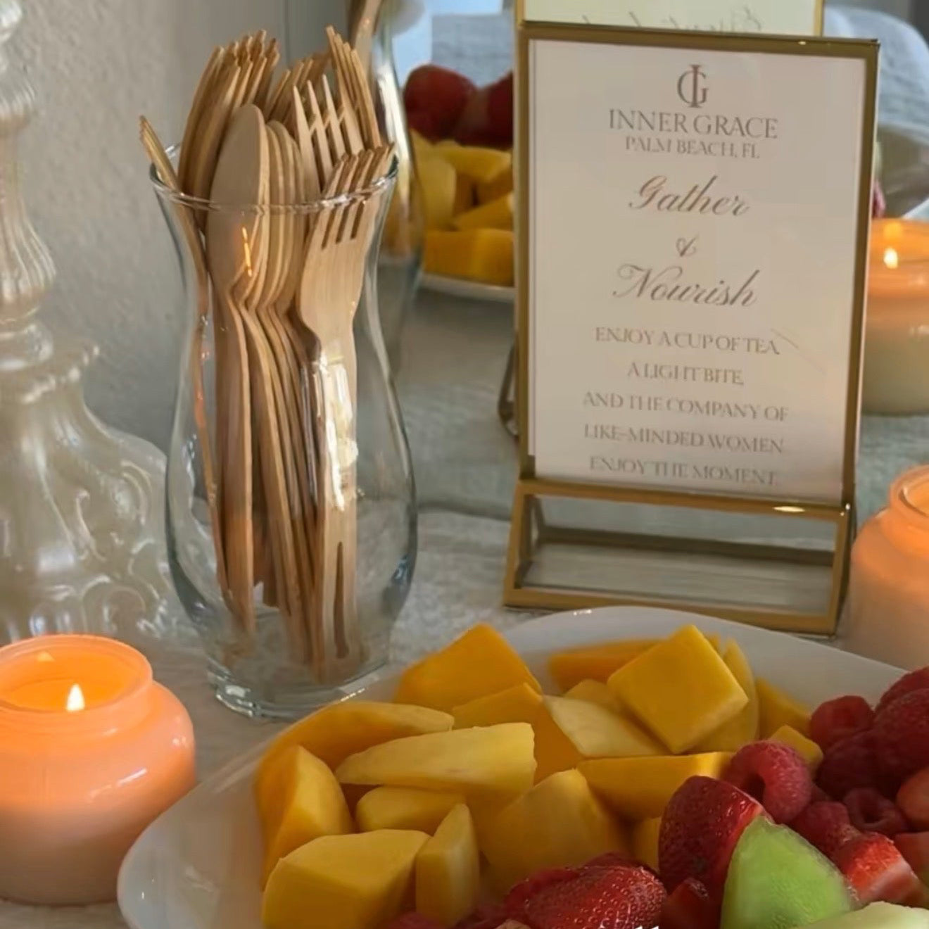 Fruit plate with croissants, candles, and a 'Gather & Feast' sign on a table.