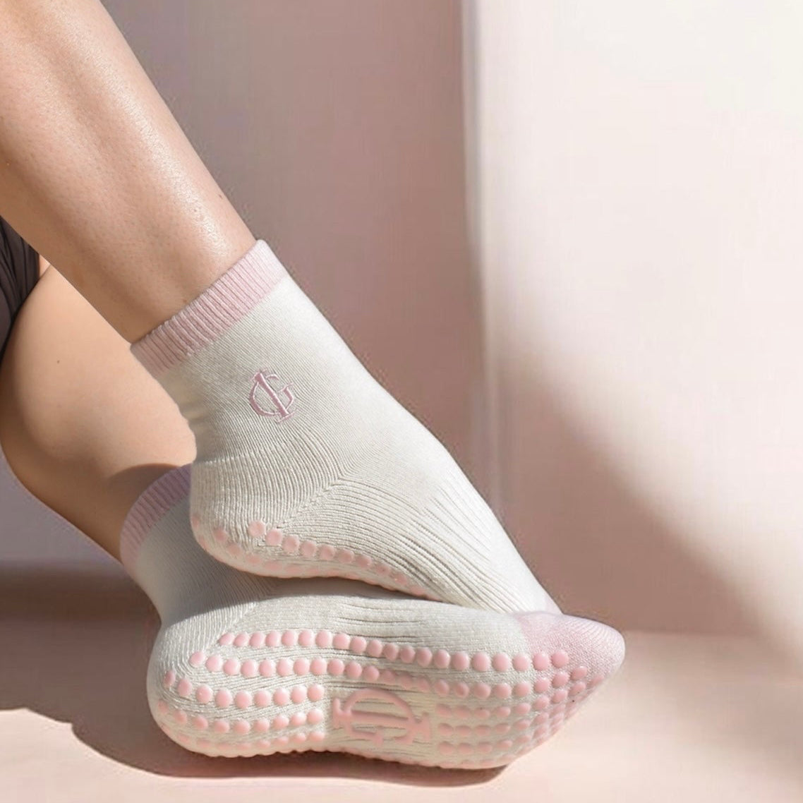 Person wearing light-colored pilates grip non slip socks on a neutral background