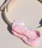Pink and cream grip pilates socks with textured sole on a beige surface for feminine soft movement